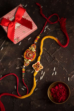 Raksha Bandhan background with an elegant Rakhi, Rice Grains, Kumkum and gift box. A traditional Indian wrist band which is a symbol of love between Brothers and Sisters.の写真素材
