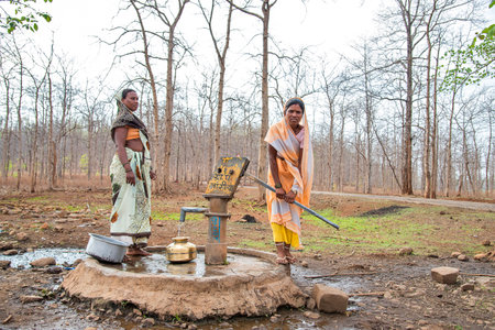 AMRAVATI, MAHARASHTRA, INDIA, 11 JUNE 2017 : Unidentified rural Indian women carry water on their heads in traditional pots from hand pump, everyday Women walk few kilometers to get it due to drought.のeditorial素材