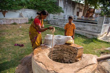 AMRAVATI, MAHARASHTRA, INDIA - JUNE 17, 2017: Unidentified women and her son from village gathering drinking water from a well.のeditorial素材