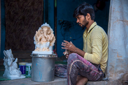 AMRAVATI, MAHARASHTRA - AUGUST 25, 2018: Artist making a statue and gives finishing touches on an idol of the Hindu god Lord Ganesha at an artist's workshop for Ganesha festival.のeditorial素材
