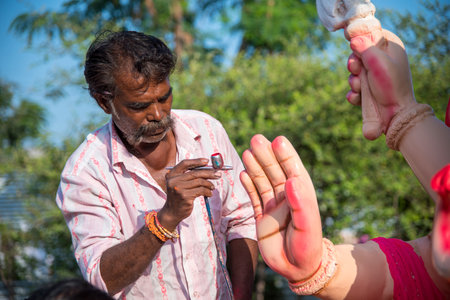 AMRAVATI, MAHARASHTRA - SEPTEMBER 8, 2018: Artist making a statue and gives finishing touches on an idol of the Hindu god Lord Ganesha at an artist's workshop for Ganesha festival.のeditorial素材