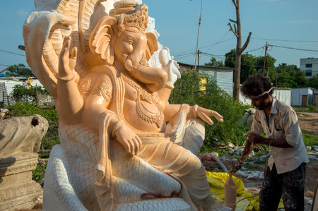 AMRAVATI, MAHARASHTRA - SEPTEMBER 8, 2018: Artist making a statue and gives finishing touches on an idol of the Hindu god Lord Ganesha at an artist's workshop for Ganesha festival.のeditorial素材