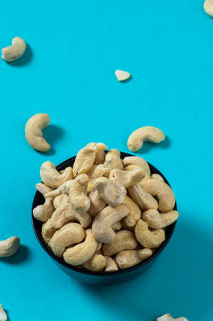 Cashew nuts in a bowl on blue backgroundの写真素材