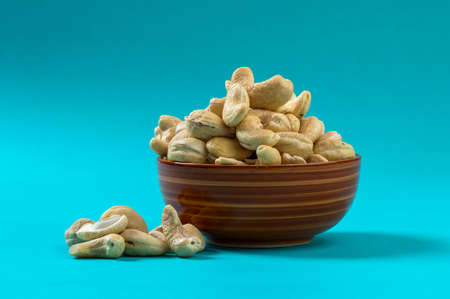 Cashew nuts in a bowl on blue backgroundの写真素材