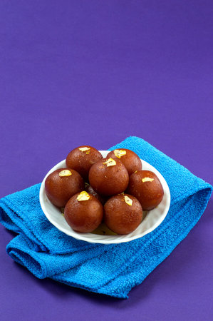 Gulab Jamun, Indian dessert topped with pistachio in white bowl with napkin