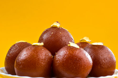 Indian Dessert or Sweet Dish : Gulab Jamun in white bowl on yellow background