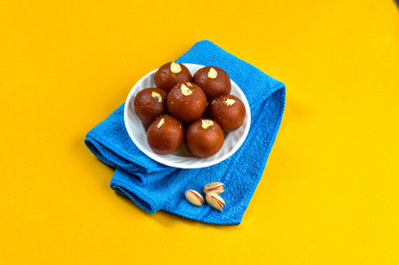Gulab Jamun, Indian dessert in white bowl with Pistachio, Almonds and Cashew on napkin