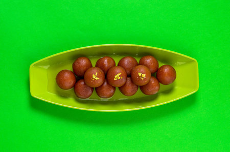 Gulab Jamun in plate on green background. Indian Dessert or Sweet Dish.