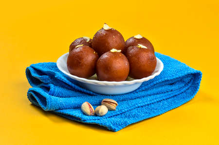 Gulab Jamun, Indian dessert in white bowl with Pistachio, Almonds and Cashew on napkinの写真素材