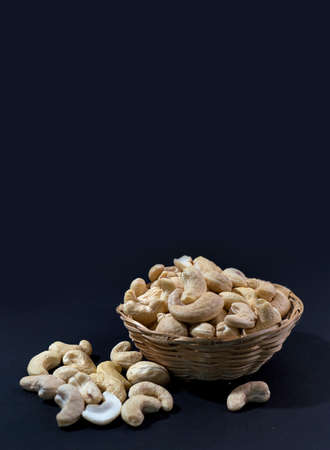 Cashew nuts in basket on black backgroundの写真素材