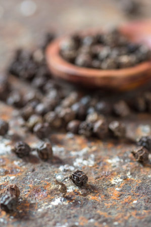 Peppercorns in wooden spoon on texture background