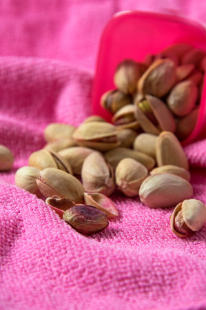 Pistachios in container on pink background