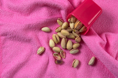 Pistachios in container on pink background