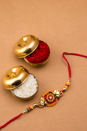 Raksha Bandhan background with an elegant Rakhi, Rice Grains and Kumkum. A traditional Indian wrist...