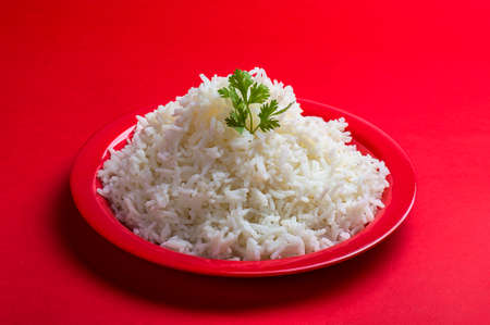 Cooked plain white basmati rice in a red plate on red backgroundの写真素材