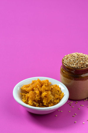 Sesame Seeds in clay pot with Jaggery in bowl on pink backgroundの写真素材