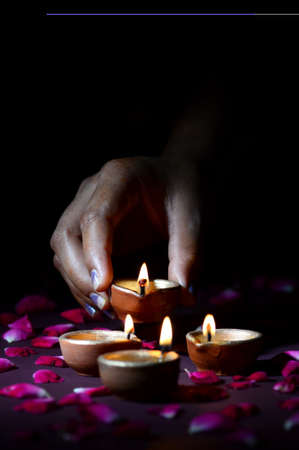 Hand holding and arranging lantern (Diya) during Diwali Festival of Lightsの写真素材