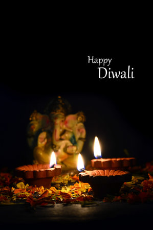 Clay diya lamps lit with Lord Ganesha during Diwali Celebration. Greetings Card Design Indian Hindu Light Festival called Diwaliの写真素材