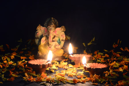 Clay diya lamps lit with Lord Ganesha during Diwali Celebration. Greetings Card Design Indian Hindu Light Festival called Diwaliの写真素材