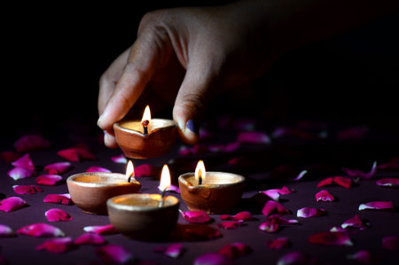 Hand holding and arranging lantern (Diya) during Diwali Festival of Lightsの写真素材