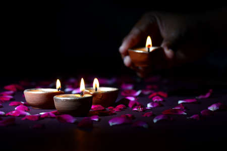 Hand holding and arranging lantern (Diya) during Diwali Festival of Lightsの写真素材