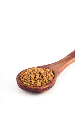 Fenugreek seeds in wooden spoon isolated on white backgroundの写真素材