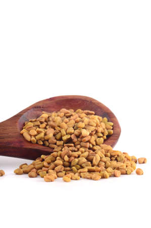 Fenugreek seeds in wooden spoon isolated on white backgroundの写真素材