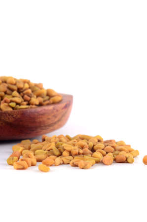 Fenugreek seeds in wooden spoon isolated on white backgroundの写真素材