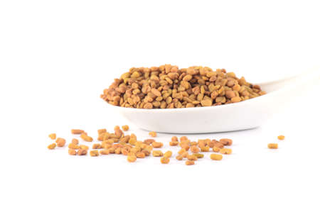 fenugreek seeds in spoon isolated on white backgroundの写真素材