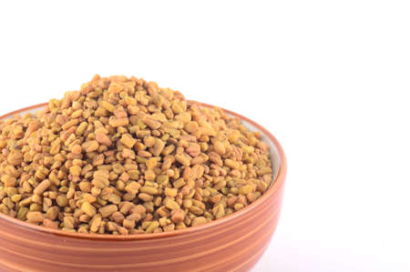 Fenugreek seeds in bowl isolated on white backgroundの写真素材