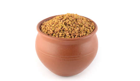 Fenugreek seeds in clay pot isolated on white backgroundの写真素材