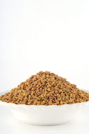 Fenugreek seeds in white plate isolated on white backgroundの写真素材