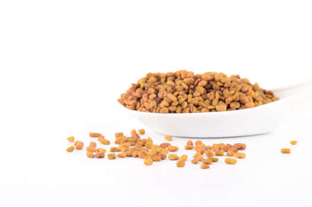 fenugreek seeds in spoon isolated on white backgroundの写真素材