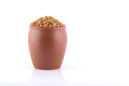 Fenugreek seeds in clay pot isolated on white backgroundの写真素材