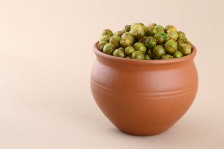 Spiced fried green peas {chatpata matar} Indian snack. Dried salted green peas in clay pot.の写真素材