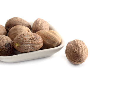 Nutmeg in white plate isolated on white backgroundの写真素材