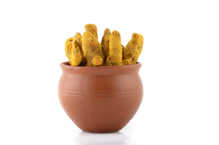 Dry Turmeric roots or barks in clay pot isolated on white background
