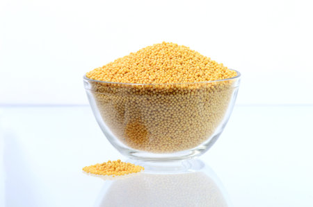 yellow mustard seeds in glass bowl isolated on white background