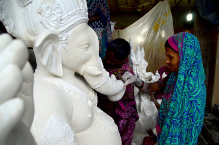 MUMBAI, MAHARASHTRA - 24 AUGUST 2014 : Artist gives finishing touches on an idol of the Hindu god Lord Ganesha at an artist's workshop for Ganesha-festival, 24 August 2014, Maharashtra, India.のeditorial素材