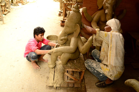 NAGPUR, MAHARASHTRA - 3 AUGUST 2014 : Artist gives finishing touches on an idol of the Hindu god Lord Ganesha at an artist's workshop for Ganesha-festival, 3 August 2014, Maharashtra, India.のeditorial素材