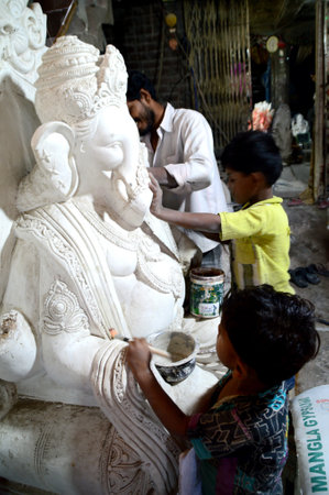 MUMBAI, MAHARASHTRA - 24 AUGUST 2014 : Artist gives finishing touches on an idol of the Hindu god Lord Ganesha at an artist's workshop for Ganesha-festival, 24 August 2014, Maharashtra, India.のeditorial素材