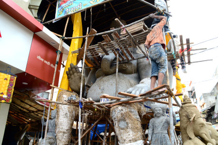 NAGPUR, MAHARASHTRA - 3 AUGUST 2014 : Artist gives finishing touches on an idol of the Hindu god Lord Ganesha at an artist's workshop for Ganesha-festival, 3 August 2014, Maharashtra, India.のeditorial素材