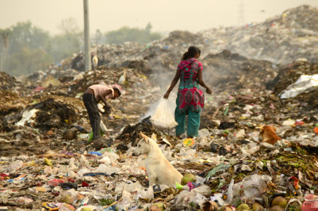 AMRAVATI, MAHARASHTRA, INDIA - APRIL 09, 2014: Unidentified rag pickers search for recyclable material in the garbage. Land and air pollution in India on April 09, 2014, Amravati, India.のeditorial素材