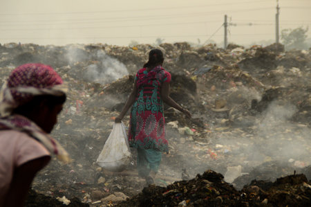 AMRAVATI, MAHARASHTRA, INDIA - APRIL 09, 2014: Unidentified rag pickers search for recyclable material in the garbage. Land and air pollution in India on April 09, 2014, Amravati, India.のeditorial素材
