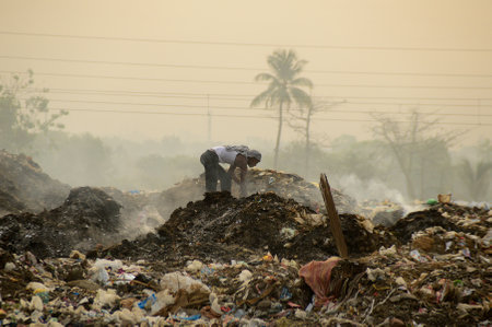 AMRAVATI, MAHARASHTRA, INDIA - APRIL 09, 2014: Unidentified rag pickers search for recyclable material in the garbage. Land and air pollution in India on April 09, 2014, Amravati, India.のeditorial素材