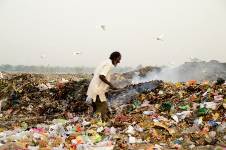 AMRAVATI, MAHARASHTRA, INDIA - APRIL 09, 2014: Unidentified rag pickers search for recyclable material in the garbage. Land and air pollution in India on April 09, 2014, Amravati, India.のeditorial素材