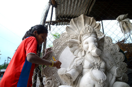 MUMBAI, MAHARASHTRA - 24 AUGUST 2014 : Artist gives finishing touches on an idol of the Hindu god Lord Ganesha at an artist's workshop for Ganesha-festival, 24 August 2014, Maharashtra, India.のeditorial素材