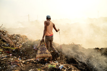 AMRAVATI, MAHARASHTRA, INDIA - APRIL 09, 2014: Unidentified rag pickers search for recyclable material in the garbage. Land and air pollution in India on April 09, 2014, Amravati, India.のeditorial素材