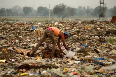 AMRAVATI, MAHARASHTRA, INDIA - APRIL 09, 2014: Unidentified rag pickers search for recyclable material in the garbage. Land and air pollution in India on April 09, 2014, Amravati, India.のeditorial素材