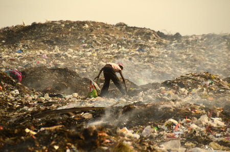 AMRAVATI, MAHARASHTRA, INDIA - APRIL 09, 2014: Unidentified rag pickers search for recyclable material in the garbage. Land and air pollution in India on April 09, 2014, Amravati, India.のeditorial素材